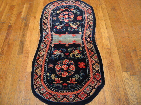 Elongated navy rug featuring coral and light blue asian patterns sits on natural wood flooring.