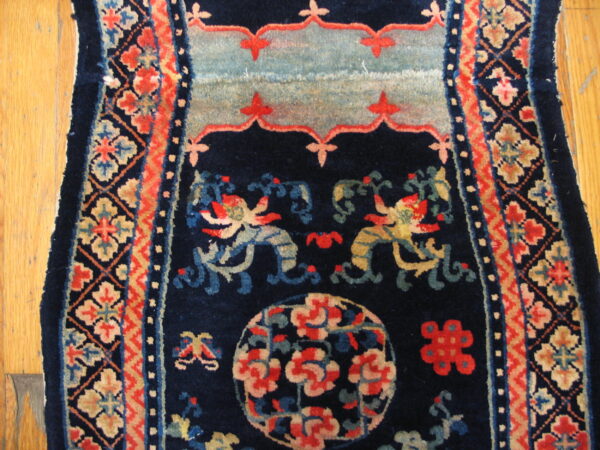 Navy rug detail showing stylized dragons, floral medallions, and geometric borders on hardwood flooring.