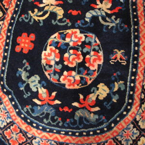Plush navy rug with stylized red and blue motifs surrounded by complex geometric borders.