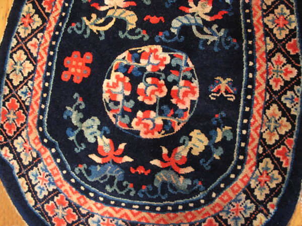 Plush navy rug with stylized red and blue motifs surrounded by complex geometric borders.
