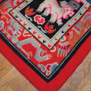 Geometric rug in red, black, pink, and gray, featuring stylized animal figures on hardwood plank flooring.