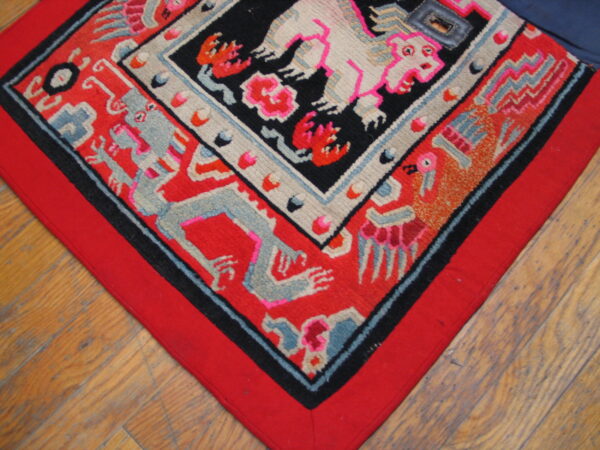 Geometric rug in red, black, pink, and gray, featuring stylized animal figures on hardwood plank flooring.
