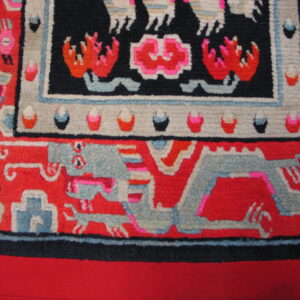 Bright red rug detail featuring a gray-blue stylized dragon and a black border with pink and orange designs.