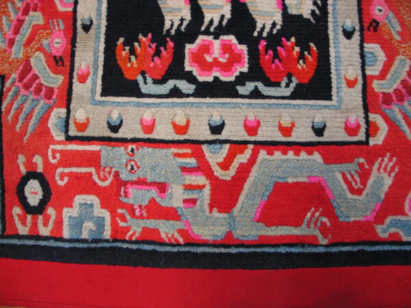 Bright red rug detail featuring a gray-blue stylized dragon and a black border with pink and orange designs.