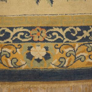 Floral and geometric borders in mustard, navy, and beige resting on light rustic wood floor.