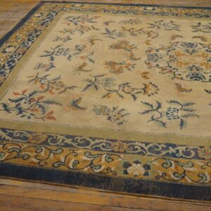 Beige rug featuring blue and gold scrolling floral patterns rests on aged wooden floorboards.