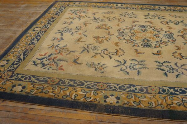 Beige rug featuring blue and gold scrolling floral patterns rests on aged wooden floorboards.