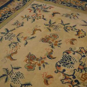 A low-pile tan rug featuring scattered floral motifs in navy, rust, and green, bordered by dark blue.