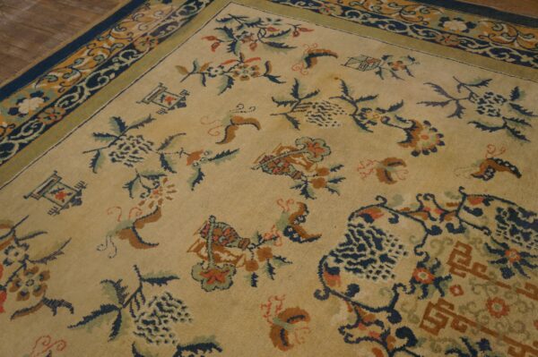 A low-pile tan rug featuring scattered floral motifs in navy, rust, and green, bordered by dark blue.