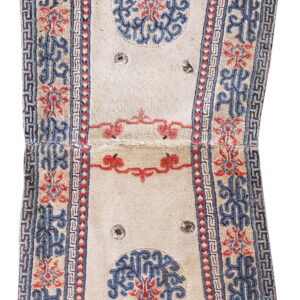 Hourglass-shaped rug with a cream field and complex blue and red scrolling floral and geometric borders.