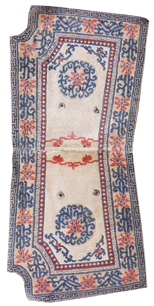 Hourglass-shaped rug with a cream field and complex blue and red scrolling floral and geometric borders.