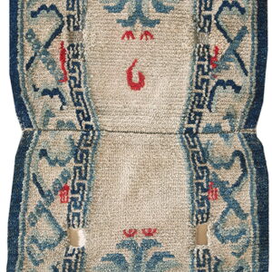 Hourglass-shaped low-pile rug with blue stylized motifs, a beige field, dark blue border, and visible wear.