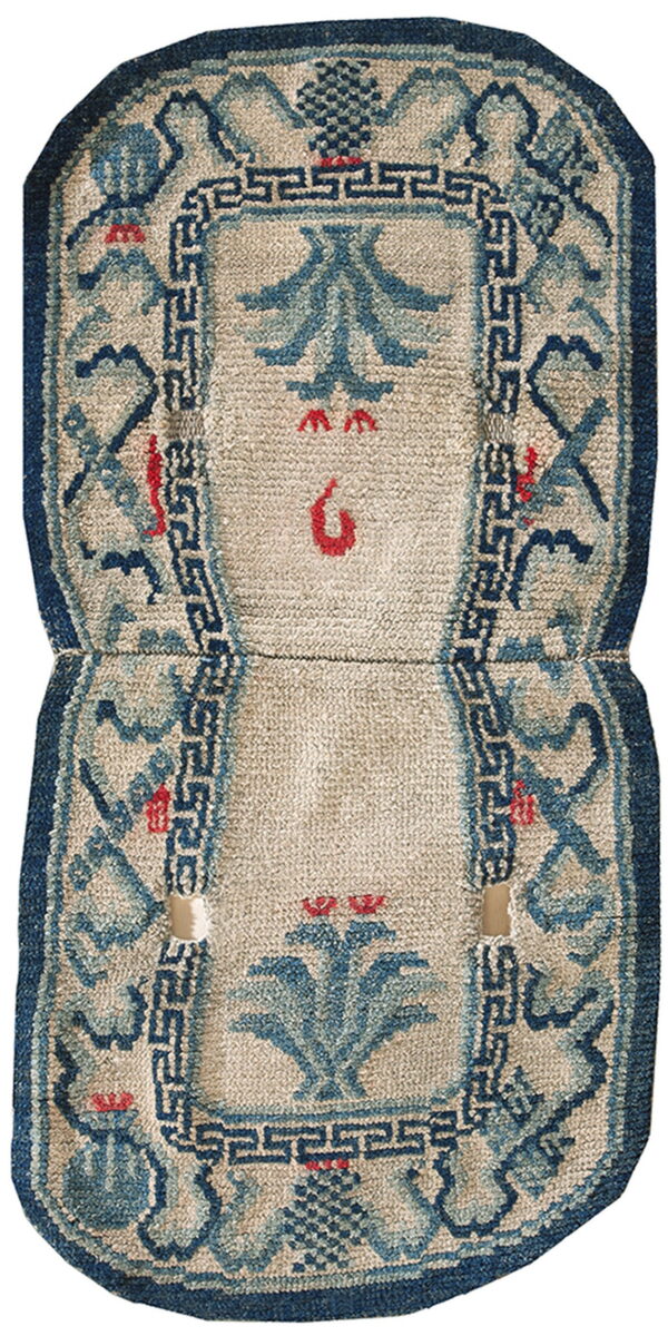 Hourglass-shaped low-pile rug with blue stylized motifs, a beige field, dark blue border, and visible wear.