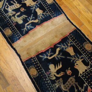 A low-pile runner with navy blue and beige stylized animal patterns lies diagonally on distressed hardwood.