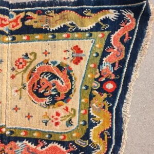 High-pile rug corner featuring complex coral and gold dragon motifs on a navy blue border.