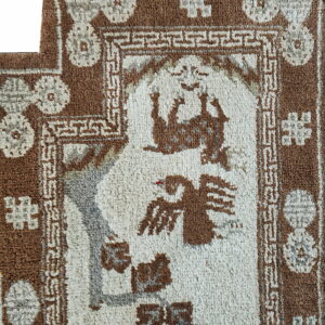 Shaggy brown and cream rug detail showing animal motifs framed by geometric borders.