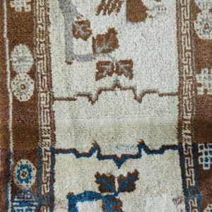 Textured rug detail in cream, brown, and blue geometric patterns rests on a light tiled floor.