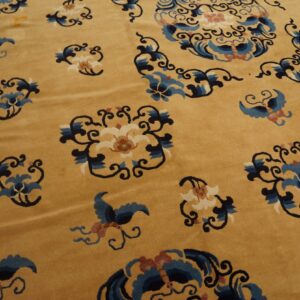 Detailed view of a gold rug featuring scattered blue, white, and black stylized floral and bird designs.
