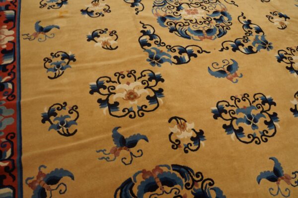 Detailed view of a gold rug featuring scattered blue, white, and black stylized floral and bird designs.