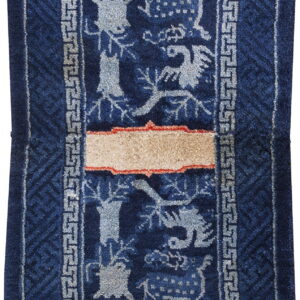 Deep blue stepped rug with light grey animal figures, Greek key border, and a contrasting tan horizontal stripe.