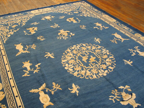 Low-pile blue rug with an ornate cream medallion and scattered light floral patterns on rustic wood planks.