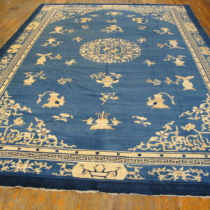 Blue rug with detailed cream traditional patterns and borders lies on hardwood flooring.