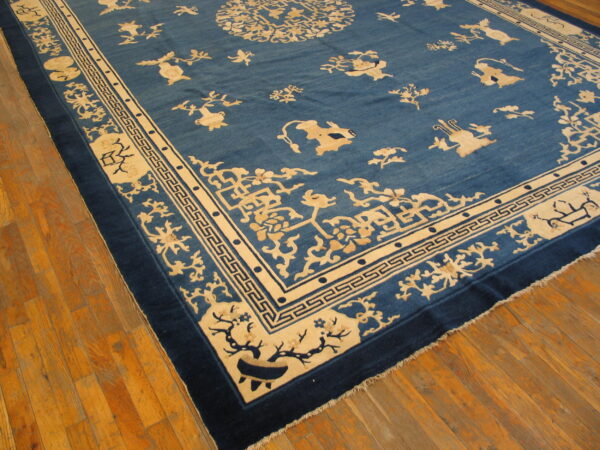 Low pile rug in deep blue and cream with stylized animals and geometric borders on hardwood flooring.