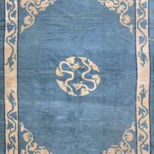 Medium blue rug featuring a wide light beige border and medallion with stylized vine patterns.