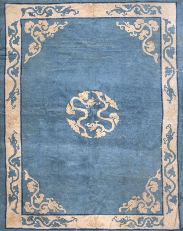 Medium blue rug featuring a wide light beige border and medallion with stylized vine patterns.