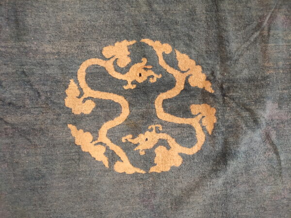 Slate blue rug with a light beige circular medallion featuring stylized dragons and swirling clouds.