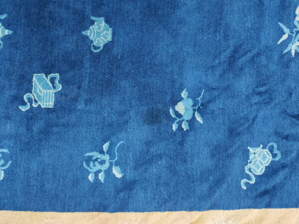 Deep blue high-pile rug with scattered light blue ornamental designs and a visible pale yellow border.