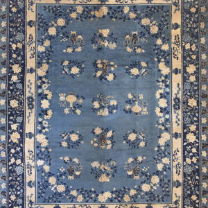 Ornate blue rug with beige and navy floral patterns and repeating vessel and bird motifs in the field.
