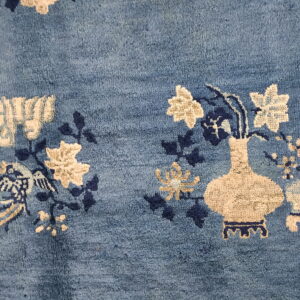 Blue rug detail showing textured pile with cream and navy floral and vase designs.