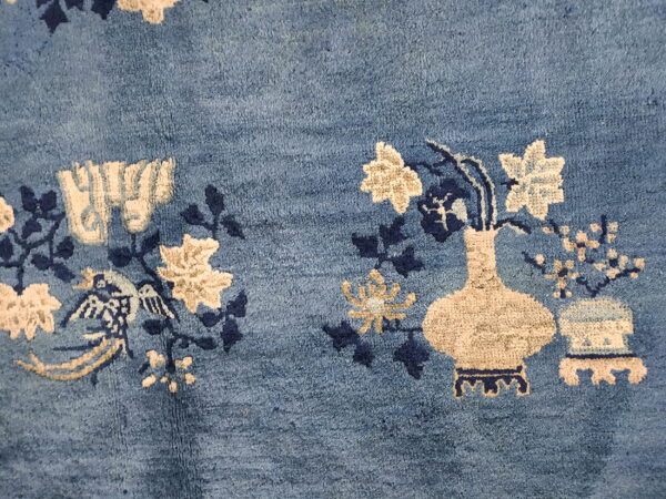 Blue rug detail showing textured pile with cream and navy floral and vase designs.