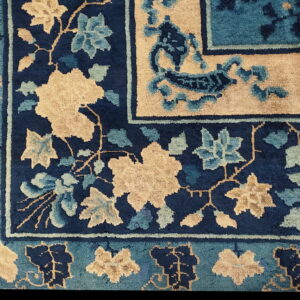 Navy blue rug detail with stylized tan and teal floral patterns defining the field and patterned borders.