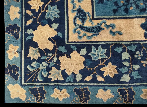 Navy blue rug detail with stylized tan and teal floral patterns defining the field and patterned borders.