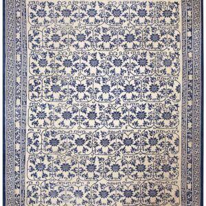 Low pile rug in blue and cream with floral medallions and a detailed Greek key border.