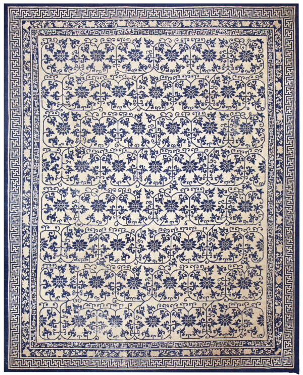 Low pile rug in blue and cream with floral medallions and a detailed greek key border.