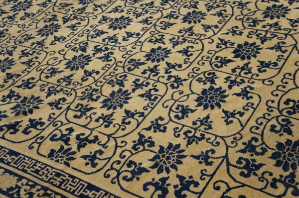 Gold and navy rug showcasing an all-over repeating floral and vine geometric lattice pattern with a border detail.