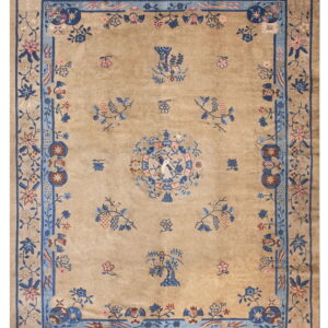 Low pile tan rug with an intricate blue and pink botanical pattern and complex border design.