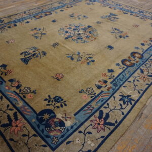 Khaki field rug with scattered blue and pink oriental floral patterns and a wide blue border.