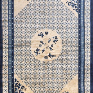 Beige and blue rug featuring a central medallion and small repeating motifs within a dark blue border.