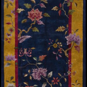 Velvety indigo rug with an elaborate floral design and a wide golden yellow border.