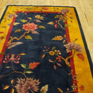 Blue floral rug with a bright yellow border sits on distressed blonde wooden floorboards.