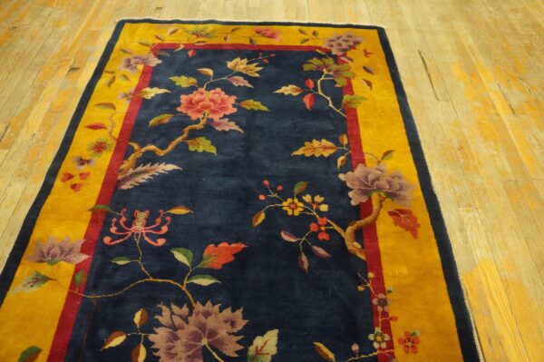 Blue floral rug with a bright yellow border sits on distressed blonde wooden floorboards.