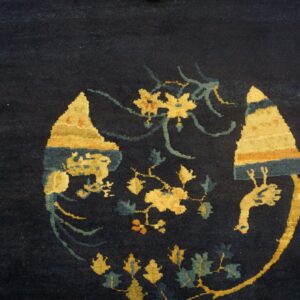 Close-up of a dark blue rug with contrasting gold, teal, and orange stylized floral and abstract motifs.