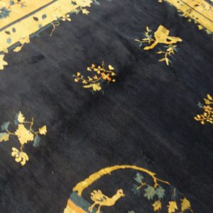 High-pile rug featuring a dark field and golden border with floral and avian designs.