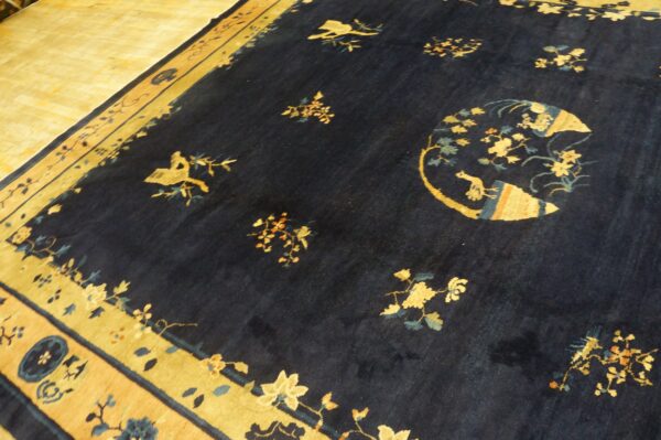 Navy blue rug featuring gold and teal scattered floral patterns and wide borders on light wood flooring.