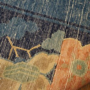 Woven rug close-up showing orange, tan, blue, and green floral patterns on navy, curling over wood planks.