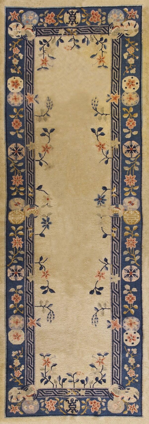 Long cream-colored runner with a floral spray pattern bordered by thick navy bands and geometric designs.
